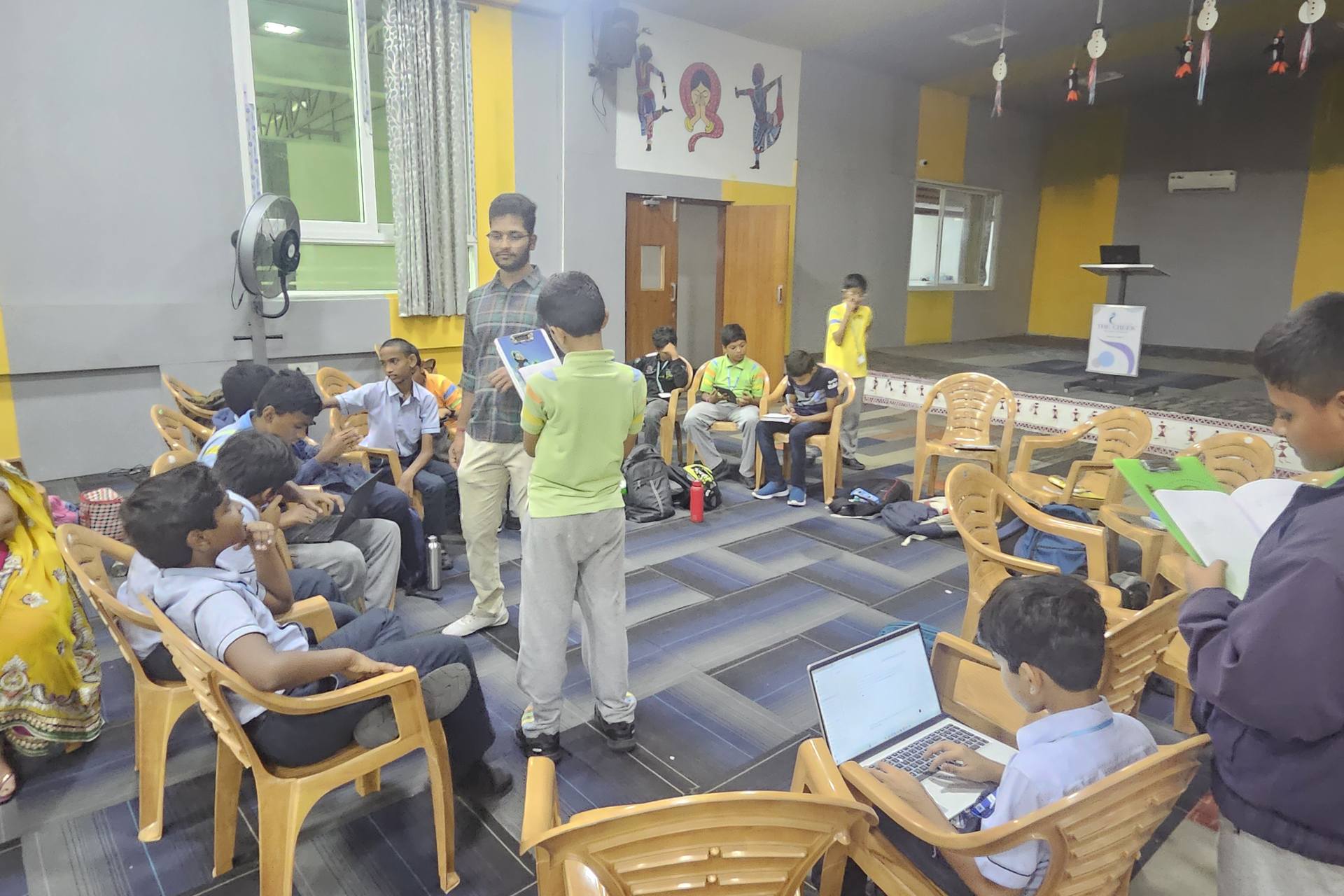A StrategyM mentor working with students seated in a circle with laptops and notebooks