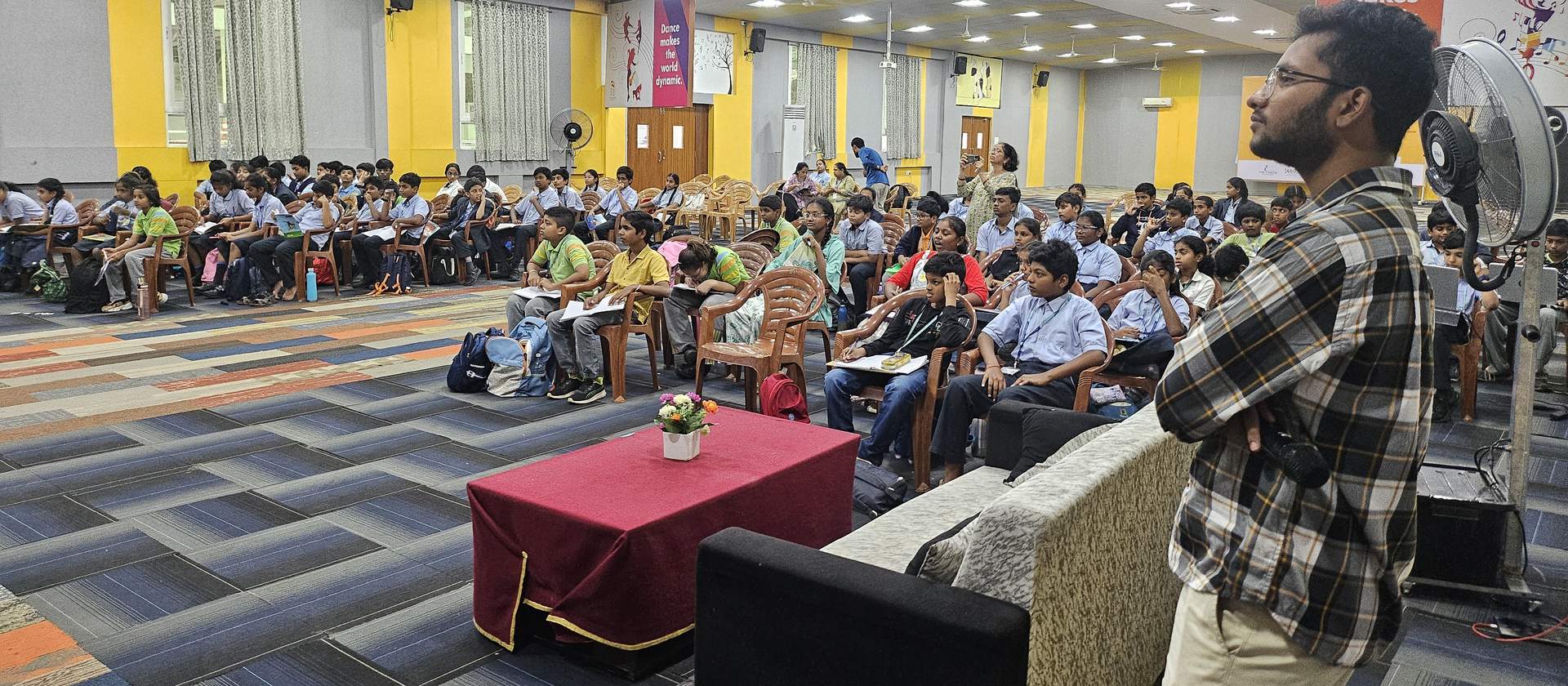 Students seated in a school hall during a StrategyM session, with a facilitator standing at the front