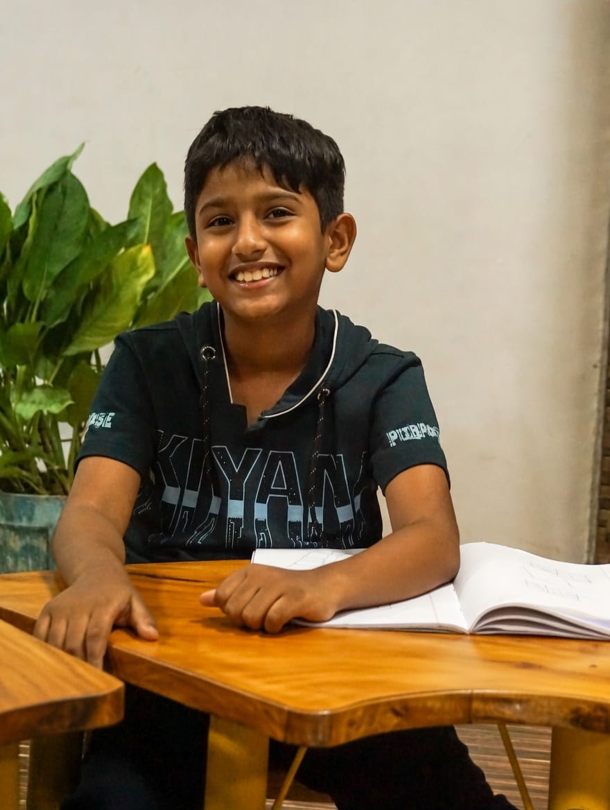 A smiling young student at a desk with an open notebook